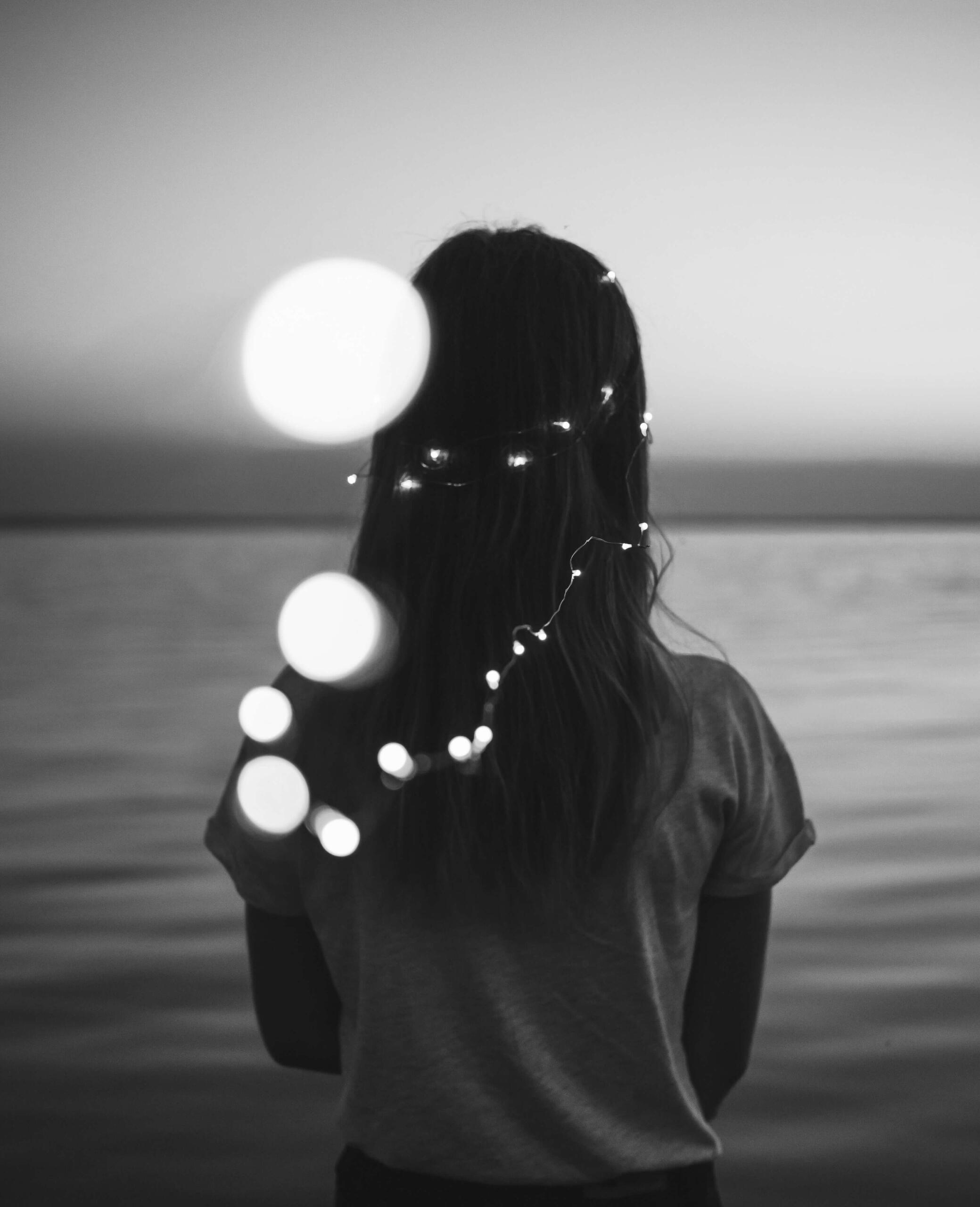 Energetic match This is a photo of a woman looking out to sea with some fairy lights